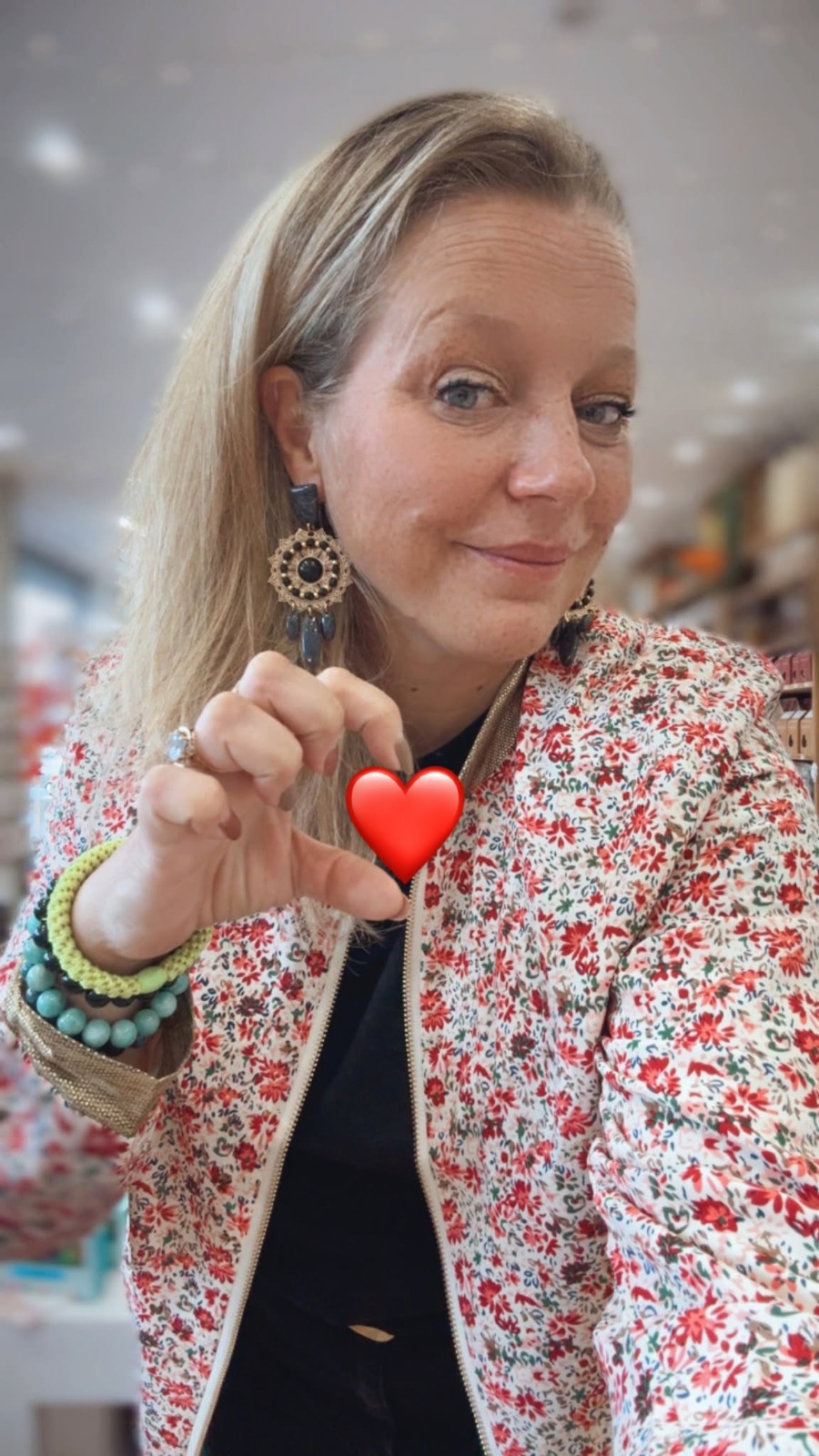 Cécile fait un cœur avec ses doigts dans sa boutique